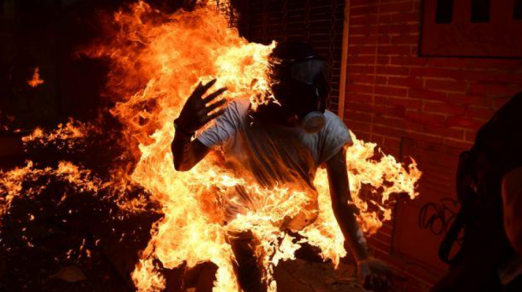 Un opositor se prende en llamas luego de lanzar una bomba lacrimógena en una protesta en la capital de Venezuela. (AFP / RONALDO SCHEMIDT).