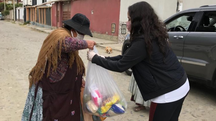 Una de las voluntarias entrega alimentos a una mamá. Foto: Una mano para mamá