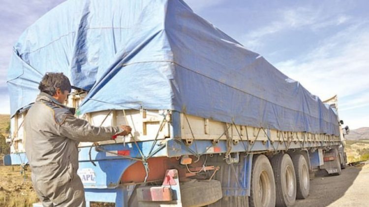 Conductor de un vehículo de transporte pesado asegurando la lona de su carrocería para evitar el robo de mercadería