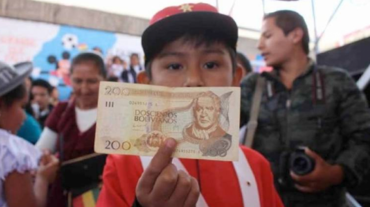 Niño recibiendo los 200 bolivianos de su bono Juancito Pinto. Foto: Página Siete