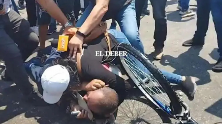 Una mujer protege con su cuerpo al periodista de Unitel, Yerko Guevara, que era golpeado por grupos afines al partido gobernante. Foto: El Deber