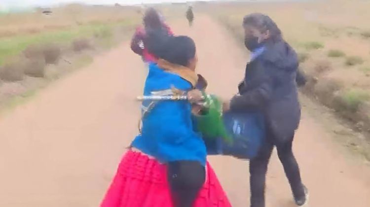 Una mujer es acechada por una señora que es parte de los ponchos rojos. Foto: Captura video Unitel.