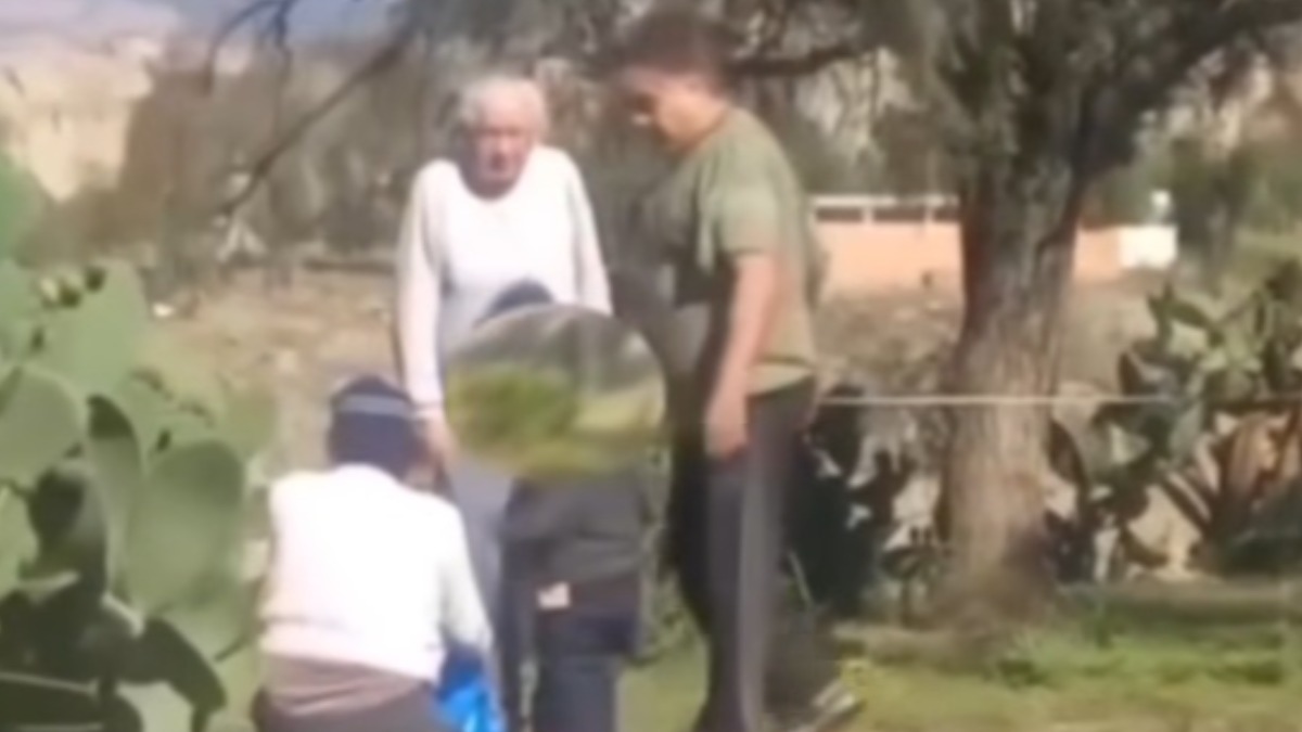 La señora de cuclillas mientras los dos hombres la reprenden. Foto: captura