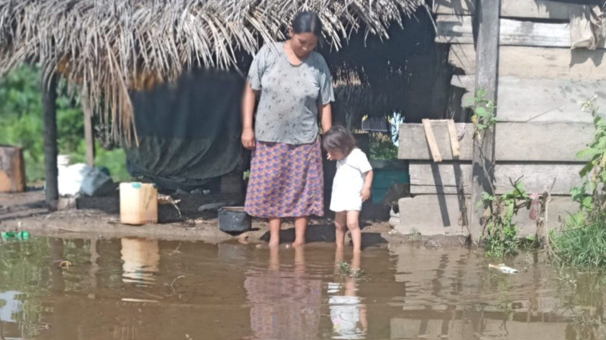 Una madre con su niña sobre el agua que llega hasta su vivienda. Foto: Territorio tsiman.